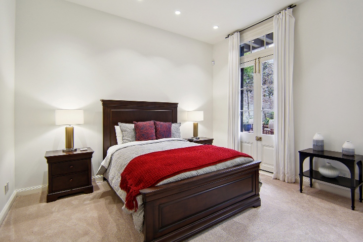 A guest bedroom with Queen-sized bed and double doors leading to a courtyard.