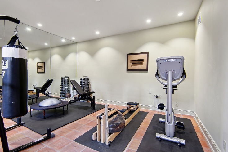 A home gym with exercise bike, rowing machine and a punching bag.