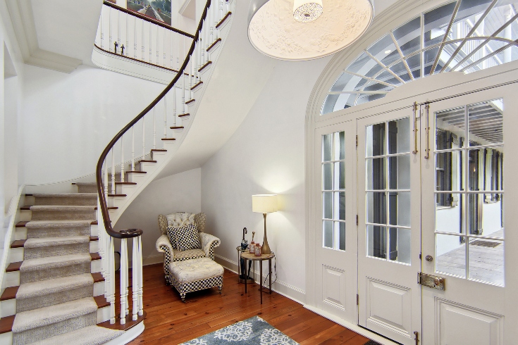 A foyer with French doors, a spiral staircase and harlequin floor tiles