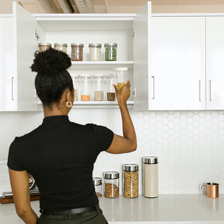 Woman organizing kitchen cupboards with pantry items