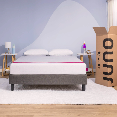 A Juno mattress fresh on the bed with the cardboard box nearby