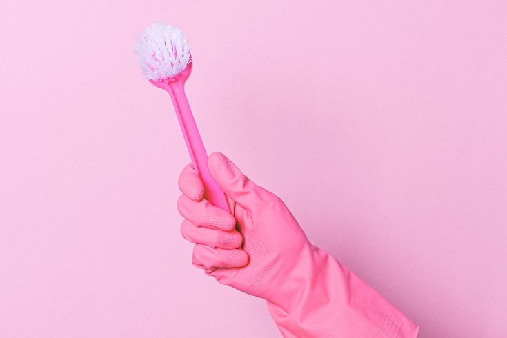 A pink glove holding a pink scrub brush