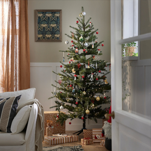 An artificial Christmas tree with colourful holiday decorations and presents underneath