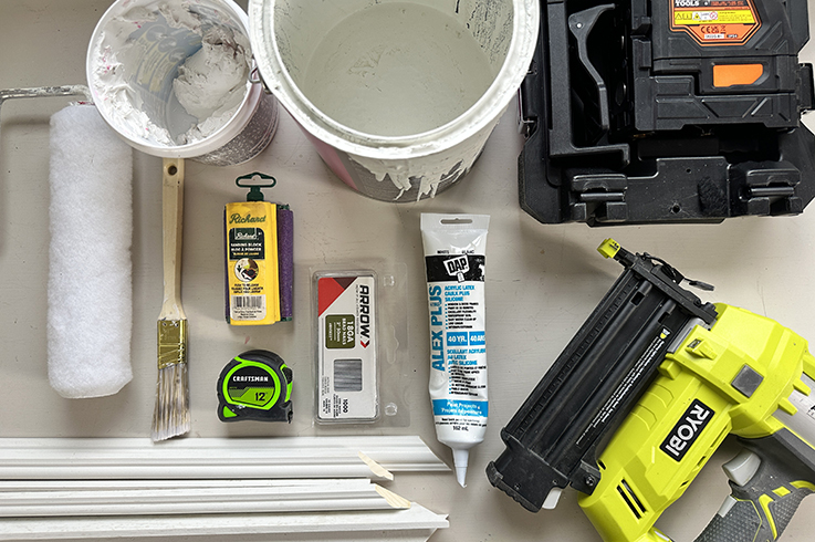 Trim moulding, laser level, pencil mitre saw, brad nailer (and nails!), paint and other supplies needed for your DIY wainscoting project.