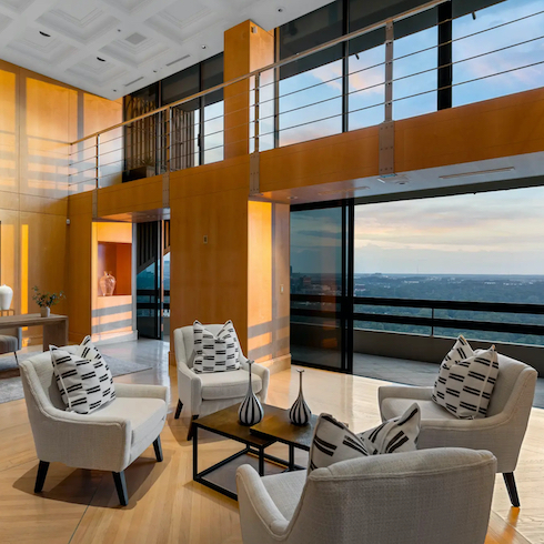 Celebrity homes - A wood-panelled gallery hall in Sir Elton John’s Atlanta, Georgia, high-rise condo with intimate seating area and a balcony with views of the city