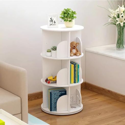 White rotating book shelf from Amazon Canada filled with books, frames, toys and plants, sitting in a corner in a room with wood floors and white walls