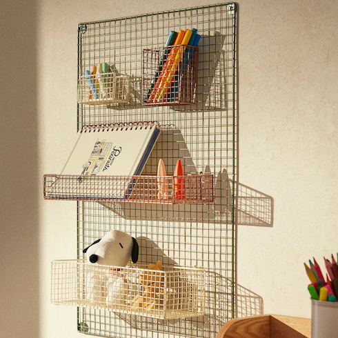Metal Hanging Organizer from Zara Home hangs on a beige wall with art supplies and stuffed animals in its wire baskets