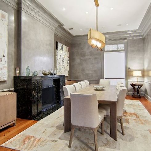 Celebrity homes - Venetian plaster walls lead from the formal living room to the formal dining room of Angelina Jolie and Brad Pitt’s former New Orleans featuring a dark marble fireplace and a door, a chandelier and a French door with balcony access