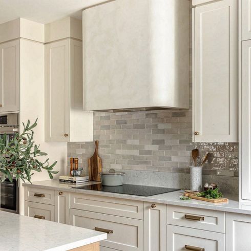 Kitchen with rounded hood vent and grey backsplash