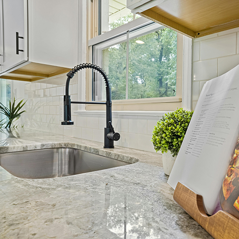 Shot of a granite countertop and sink alongside an open cookbook