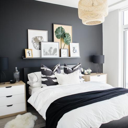Chic and curated black and white bedroom designed by Natalie Chong of Nest Design Studios featuring a matte black statement wall to frame the bed and side tables