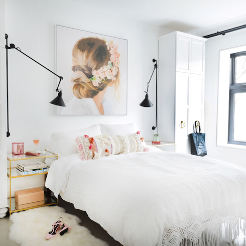 White bedroom with black sconces and art of back of woman's head with flowers in hair