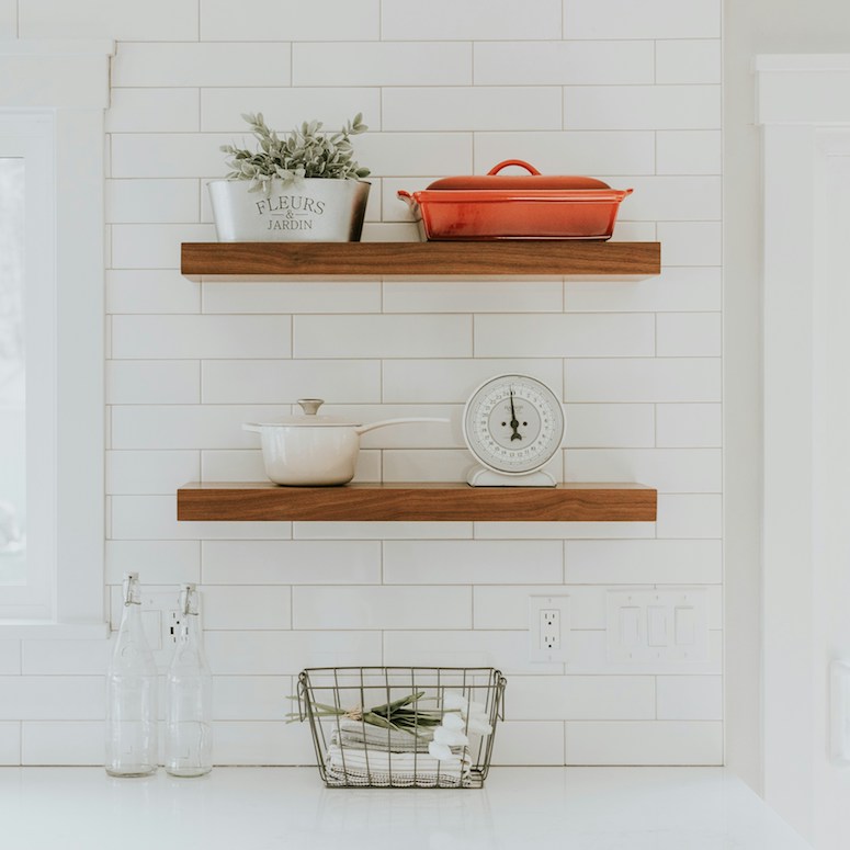 Floating wood shelves on brick backsplash in a kitchen