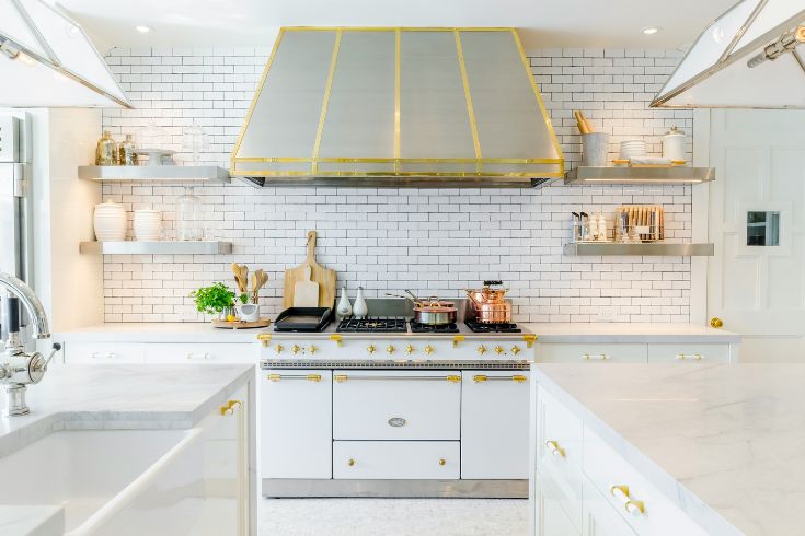 Modern white kitchen with brass-detailed hood vent and open shelving