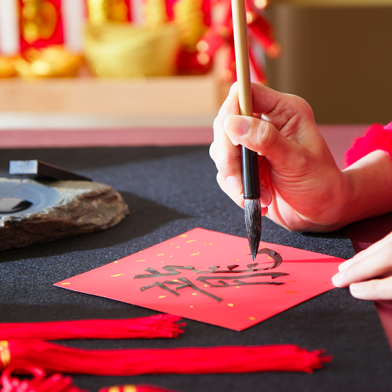 close up writing spring festival couplet to celebrate Chinese new year with word meaning Dragon