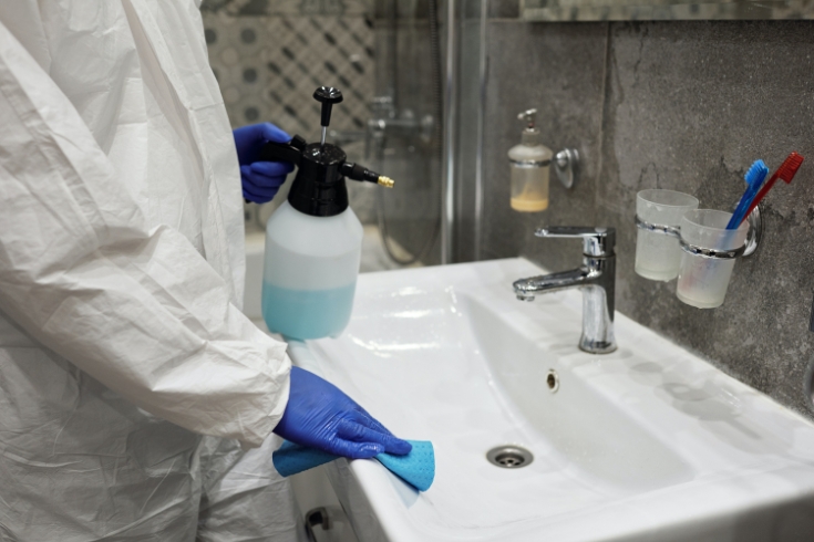 A person cleaning a bathroom in PPE gear 