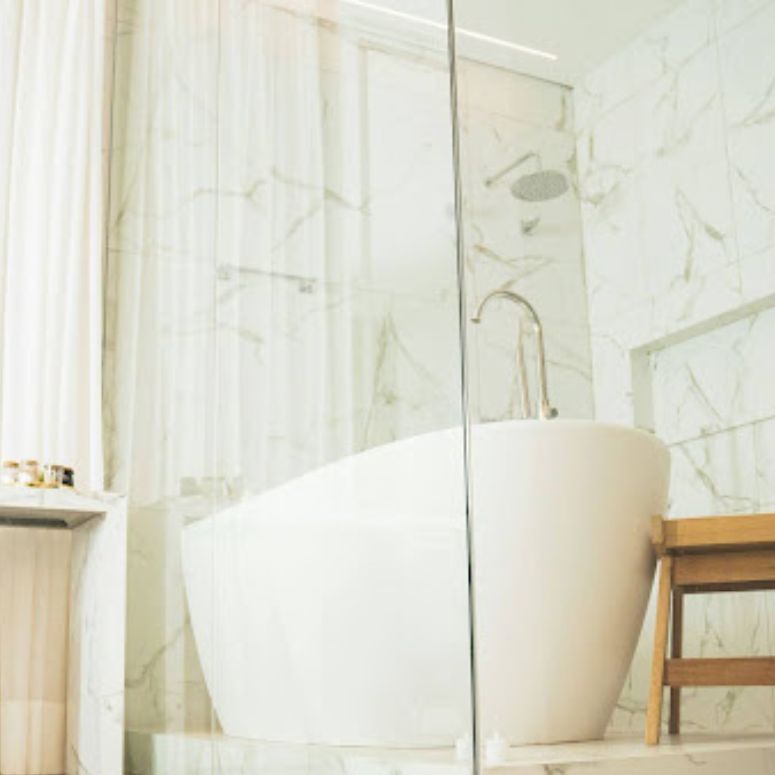 A modern white bathtub placed within a glass shower enclosure