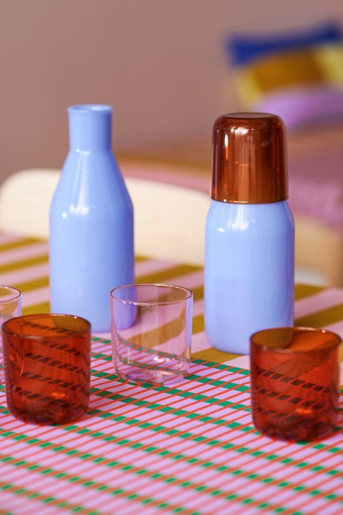 Brown and pink drinking glasses with light blue water carafes.