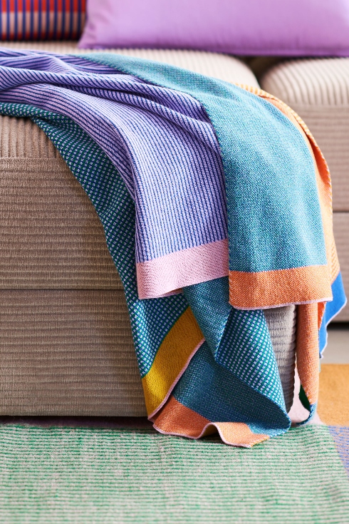 A throw blanket with with graphic lines and solid colours.