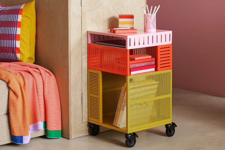 A trolley storage cart in mustard yellow, bright orange and light pink.