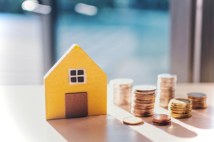 Image of miniature wooden house with coins beside it signifying mortgage rates.
