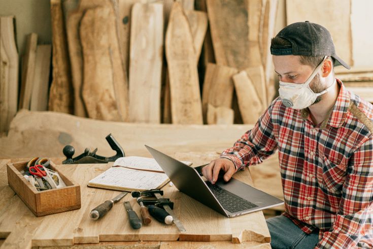 Man at a laptop in a woodshop 