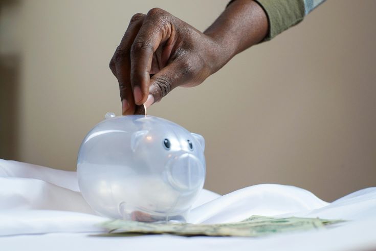 A hand filling a piggy bank with coins