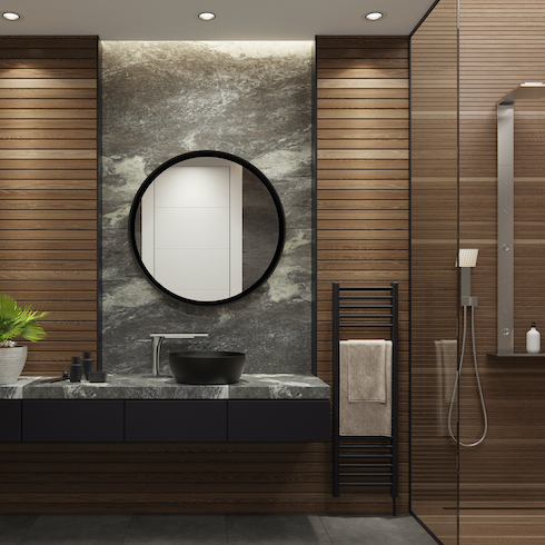 Luxurious bathroom with natural stone tiles and wood planks, a grey stone vanity with a black vessel sink, a white potted plant, black framed round mirror, potted lights on a low light, a black towel rack, and a glass shower with silver hardware