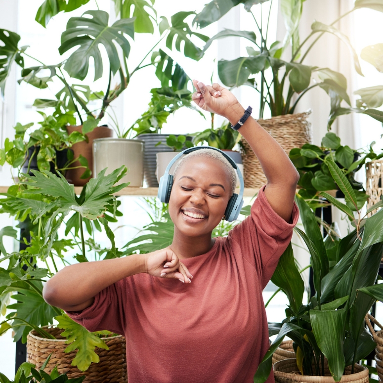 Woman singing and listening to music surrounded by her plants