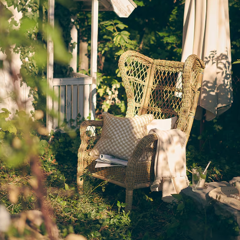 The RISHOLMEN Wicker chair from IKEA in a lush green backyard