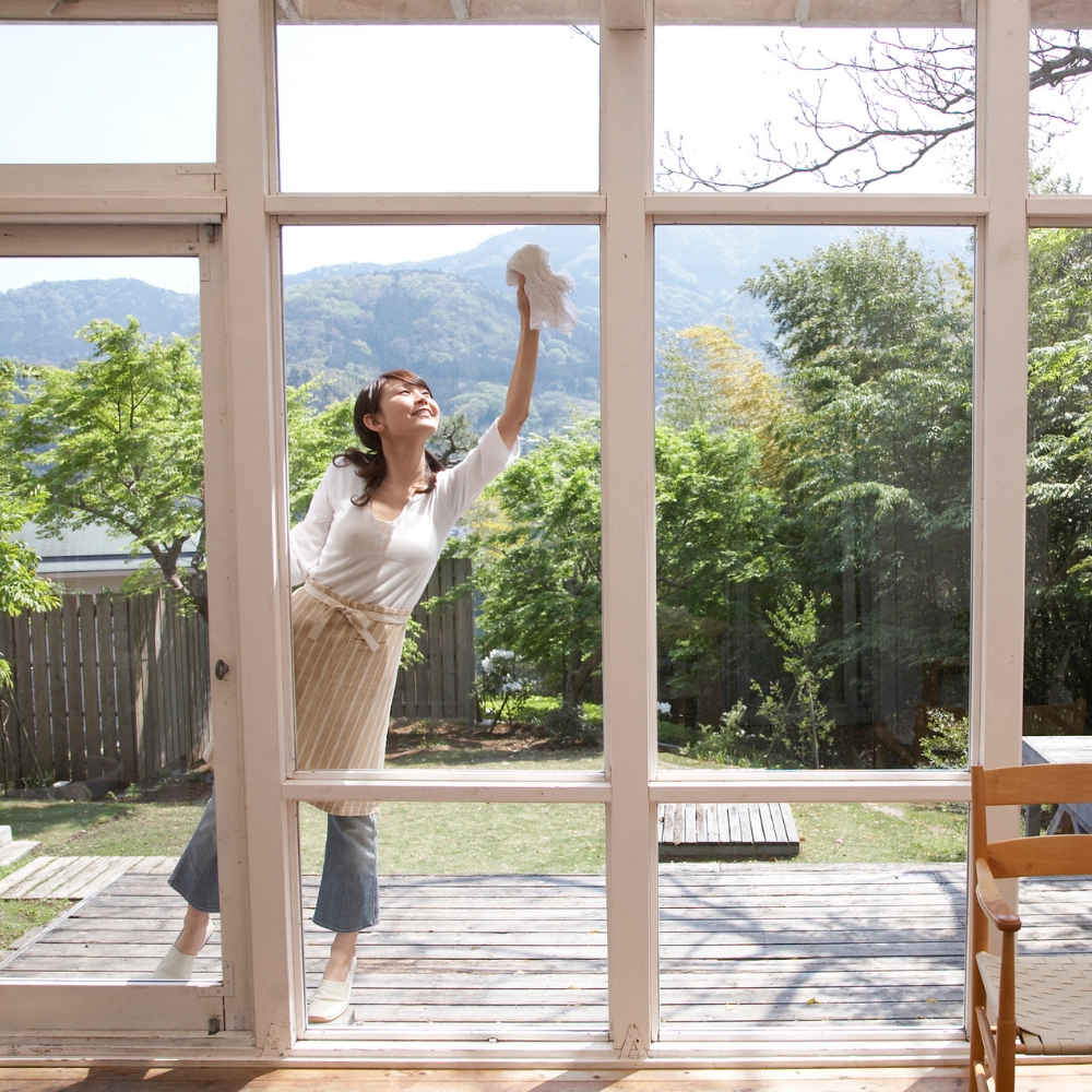 Asian woman cleaning her windows outside on a spring day