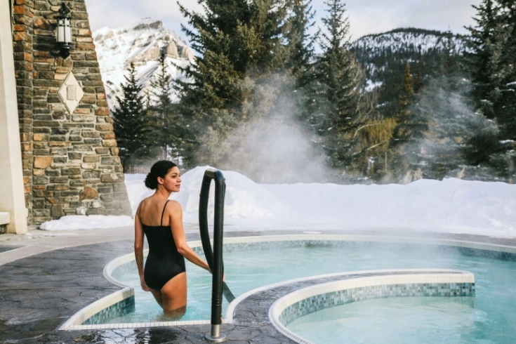 A woman stepping into an outdoor mineral pool at the Fairmont Spa Banff Springs