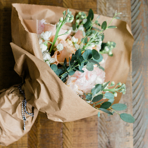 A bouquet of wildflowers wrapped in brown paper