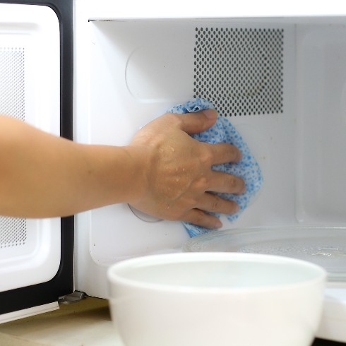 person cleaning a microwave oven
