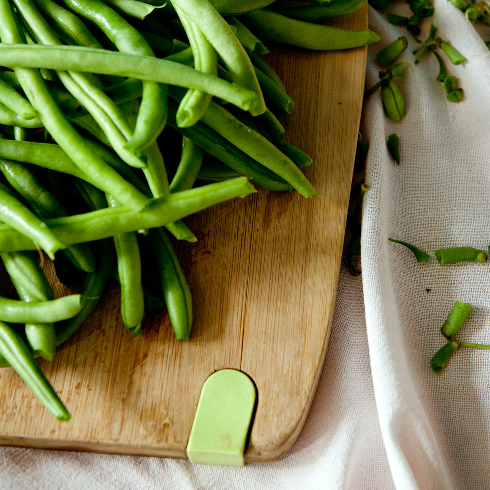 A wooden cutting board with fresh green beans