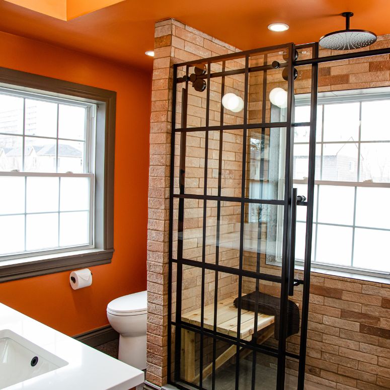 Orange wall bathroom with brown tile in the shower