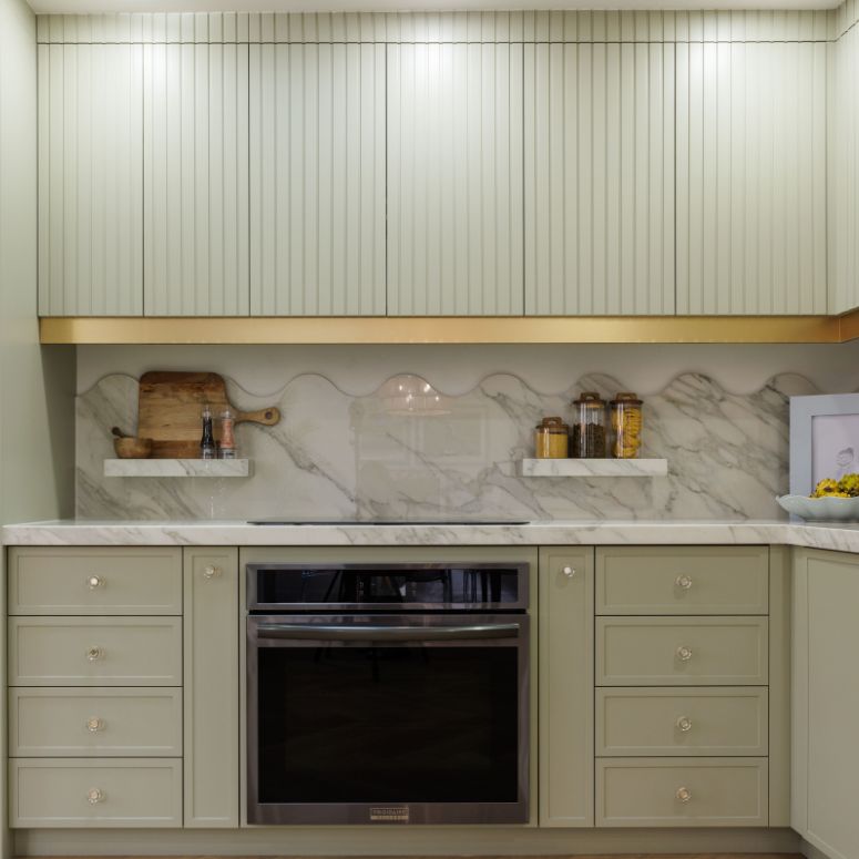 Sage green kitchen cabinets with a white marble backsplash