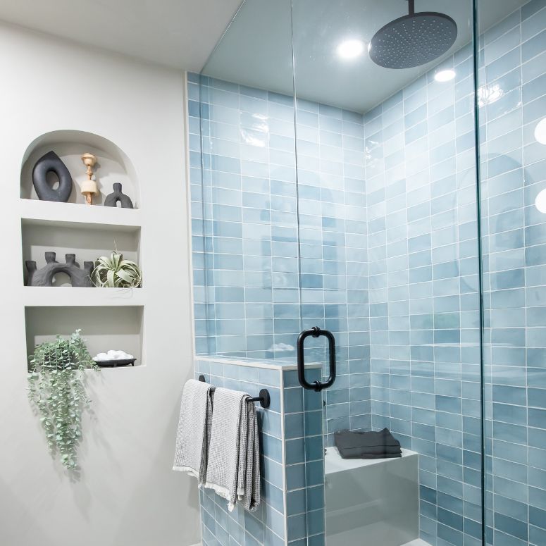 Bright bathroom with light blue tile, rain shower and in wall shelf on the left